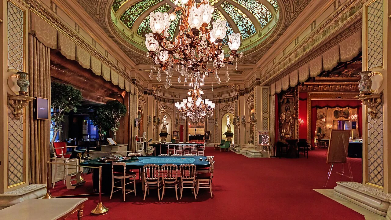 A decorated casino salon in Baden-Baden with a chandelier, painted ceiling and gaming tables