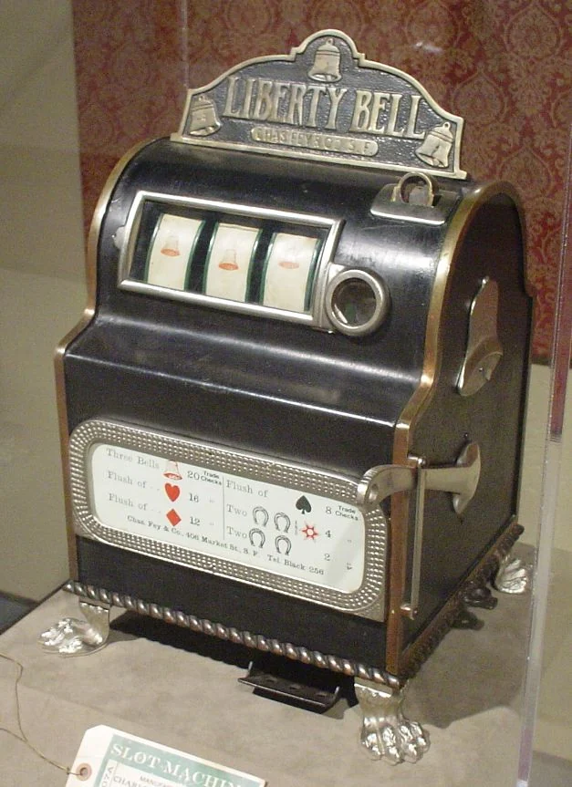 A surviving Liberty Bell mechanical slot machine with its lever and three reel windows